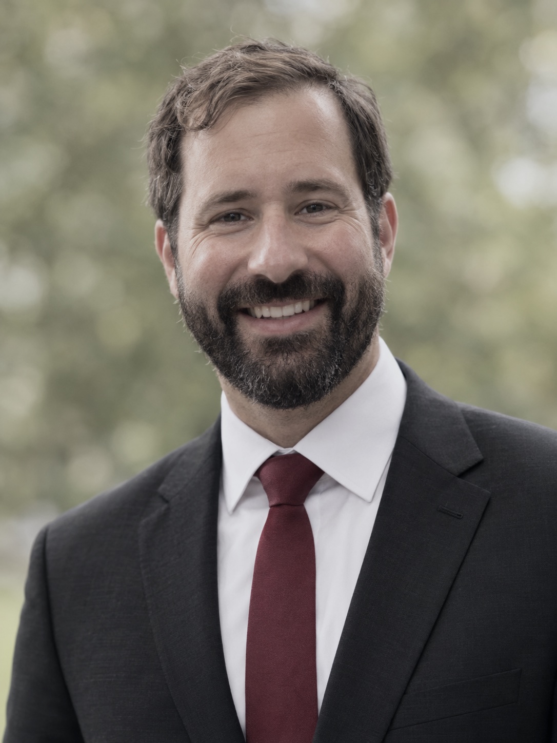 Jacob Davis, smiling, in a dark suit and red tie